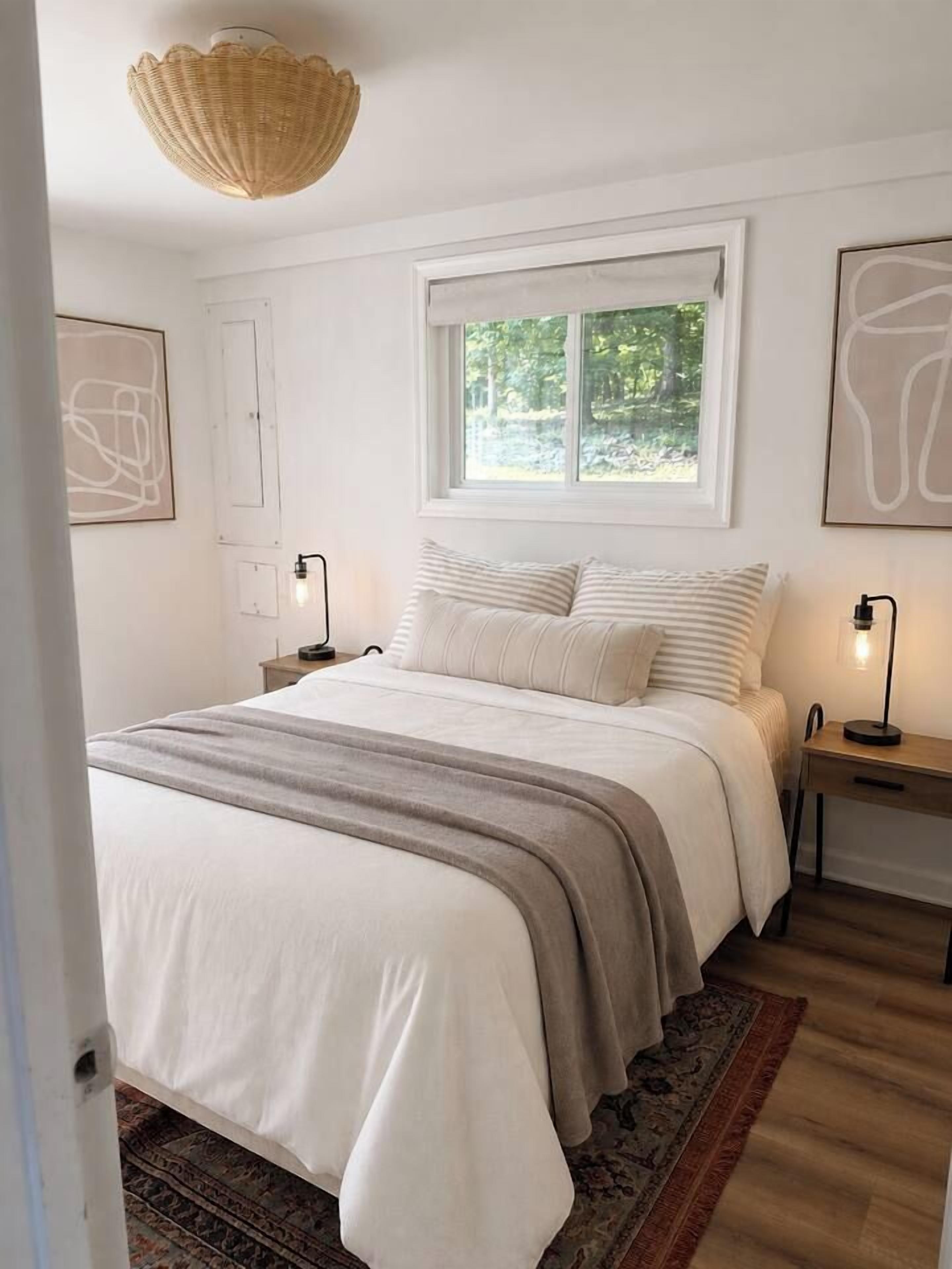 Una camera da letto con un letto, lampade sui comodini, una finestra e un lampadario.