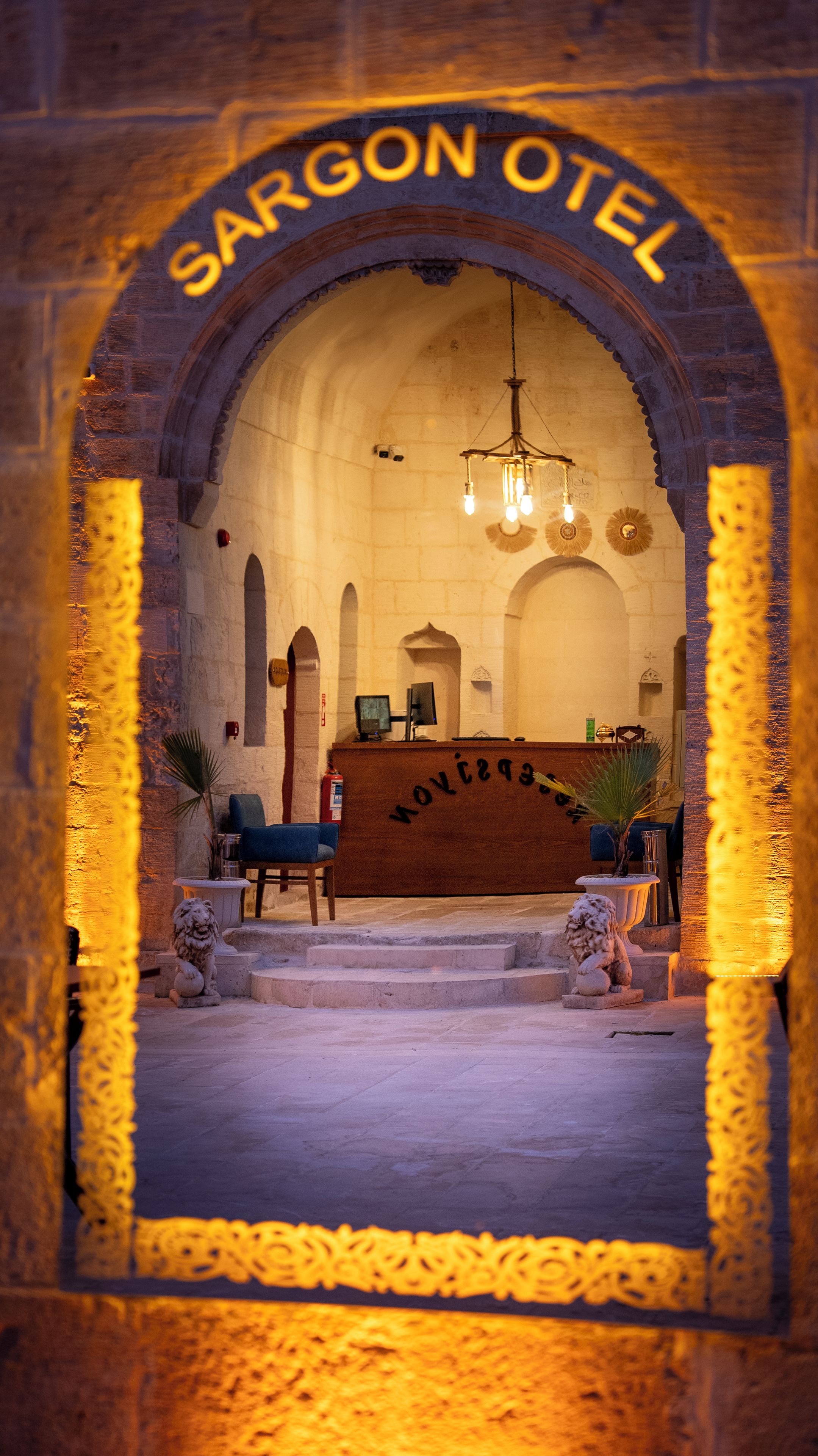 Vista del interior del Hotel Sargon, con mostrador de recepción, zona de estar y un candelabro.