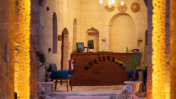 Vista del interior del Hotel Sargon, con mostrador de recepción, zona de estar y un candelabro.