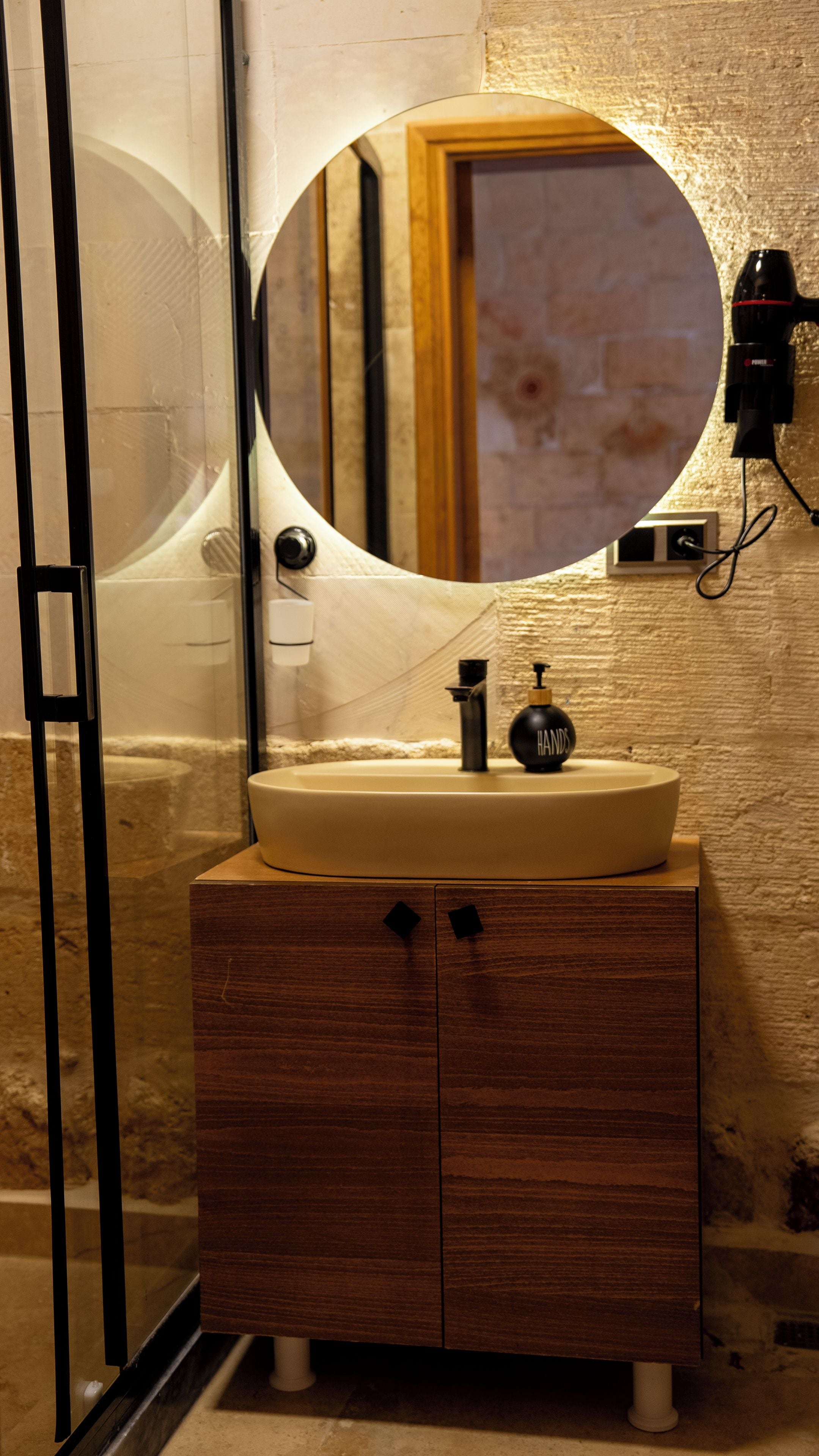 A bathroom with a round mirror, a sink, and a wooden cabinet.