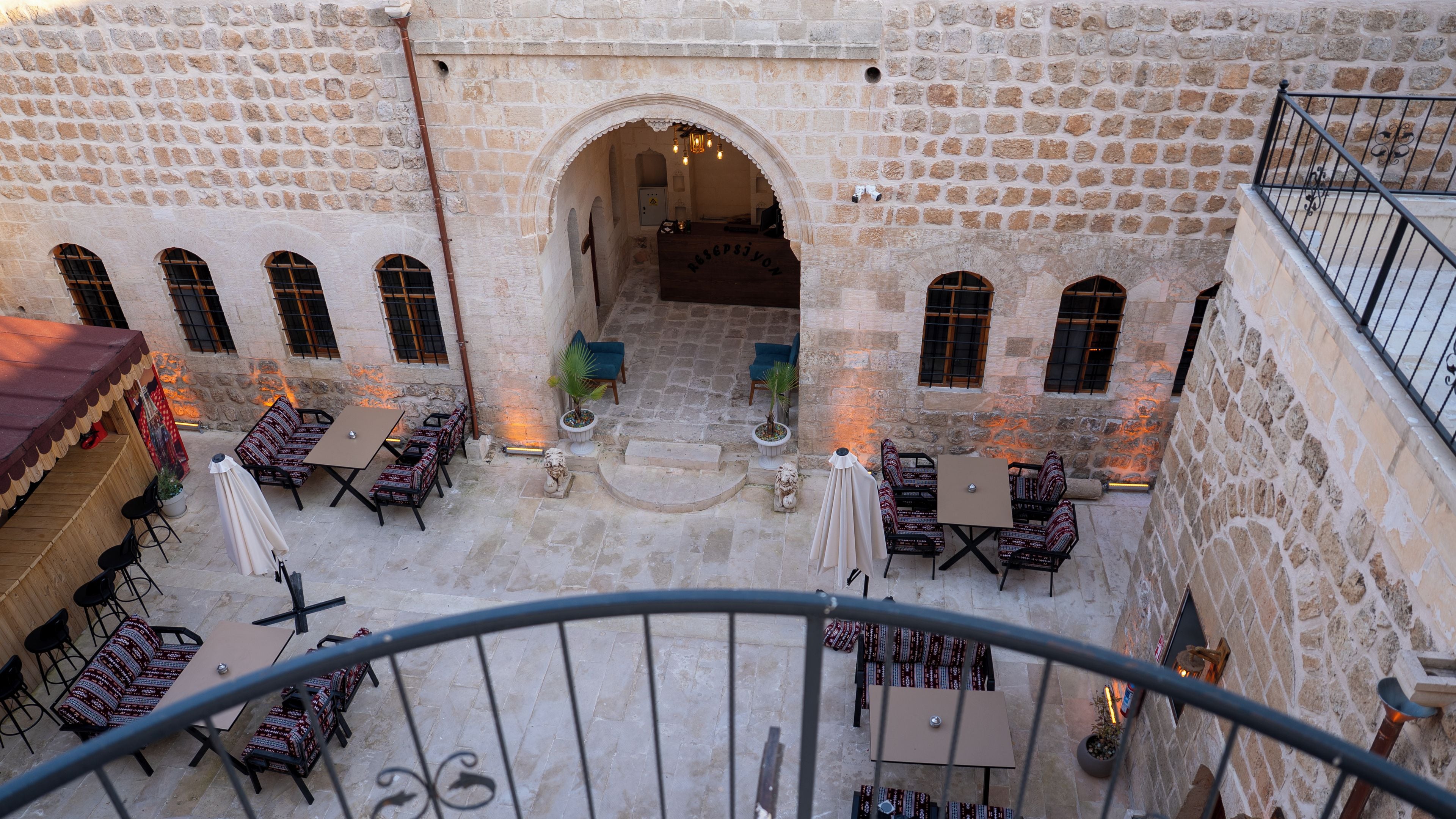 A courtyard with stone walls, outdoor seating, and a staircase leading to an upper level.