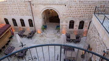 A courtyard with stone walls, outdoor seating, and a staircase leading to an upper level.