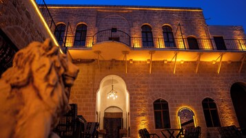 A stone building with arched windows and a staircase leading to a balcony.
