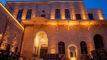 Un edificio histórico con paredes de piedra, ventanas en arco y un balcón con barandilla de metal.