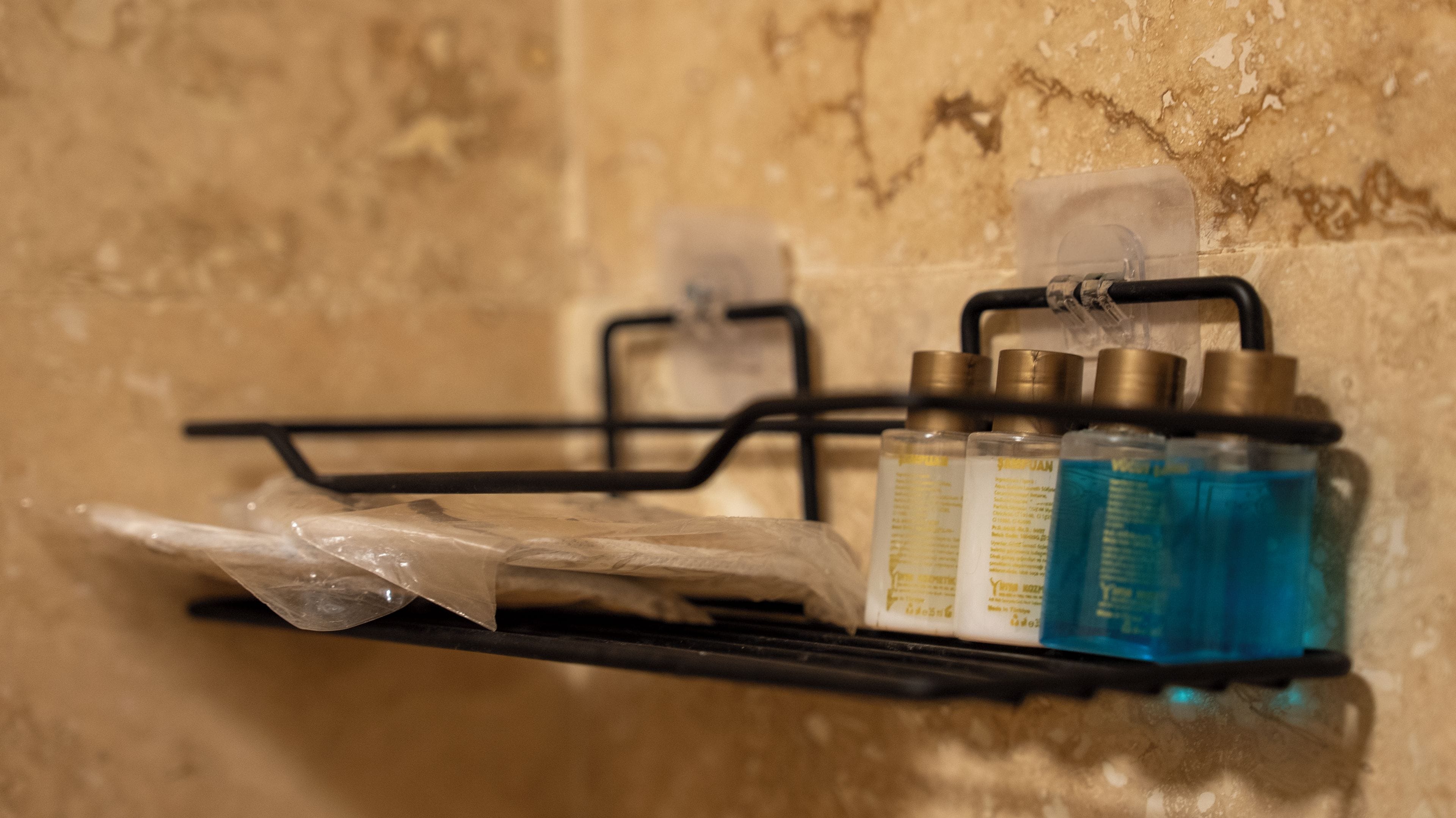 Uno scaffale in bagno con articoli da toilette, tra cui bottiglie e un sacchetto di plastica.