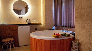 A bathroom with a wooden vanity, a sink, a mirror, and a bathtub with fruit on the edge.