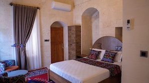 A bedroom with a bed, a wooden door, an air conditioning unit, and a window with curtains.