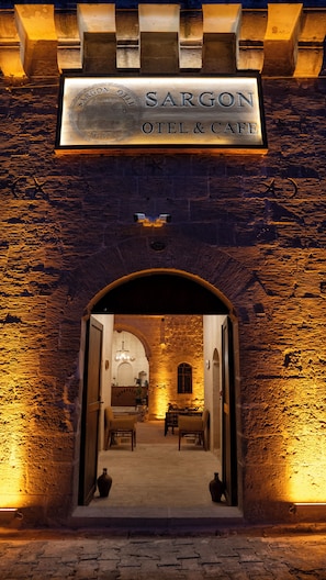 The entrance to Sargon's Hotel & Cafe with a stone archway and a sign above.