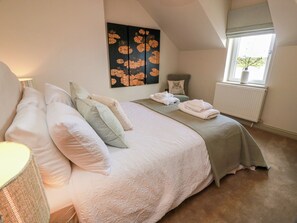 A bedroom with a bed, pillows, a radiator, a window, and a wall art piece. - Sandy Toes (Annan)