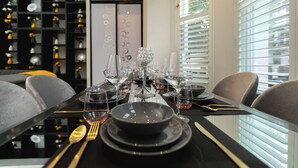 Una tavola imbandita con più bicchieri da vino, piatti e posate, con un elemento decorativo al centro.
