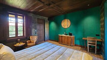 Une pièce comprenant un lit, une chaise en bois, une armoire et un mur orné d’un motif circulaire.