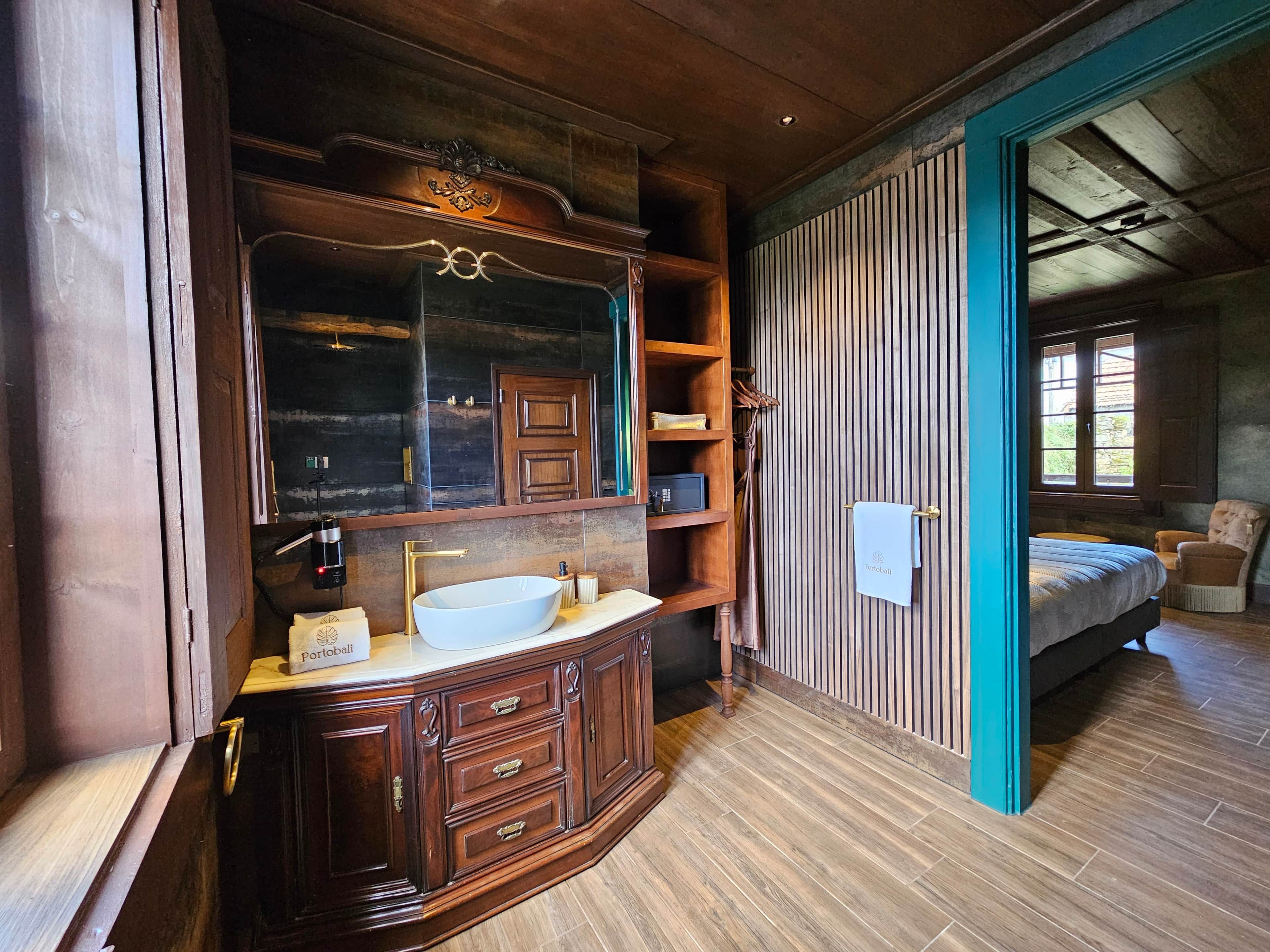 Un bagno in legno con uno specchio grande, un lavandino e un asciugamano appeso a un porta-asciugamani.