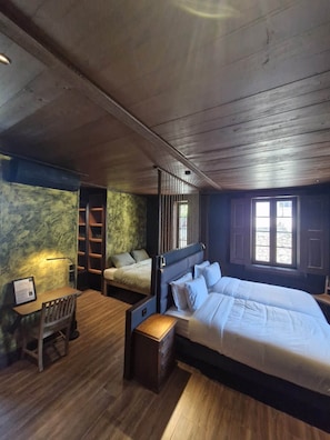Ein Schlafzimmer mit einem großen Bett, einem Schreibtisch und einem Stuhl. Ein Fenster bietet einen Ausblick nach draußen.