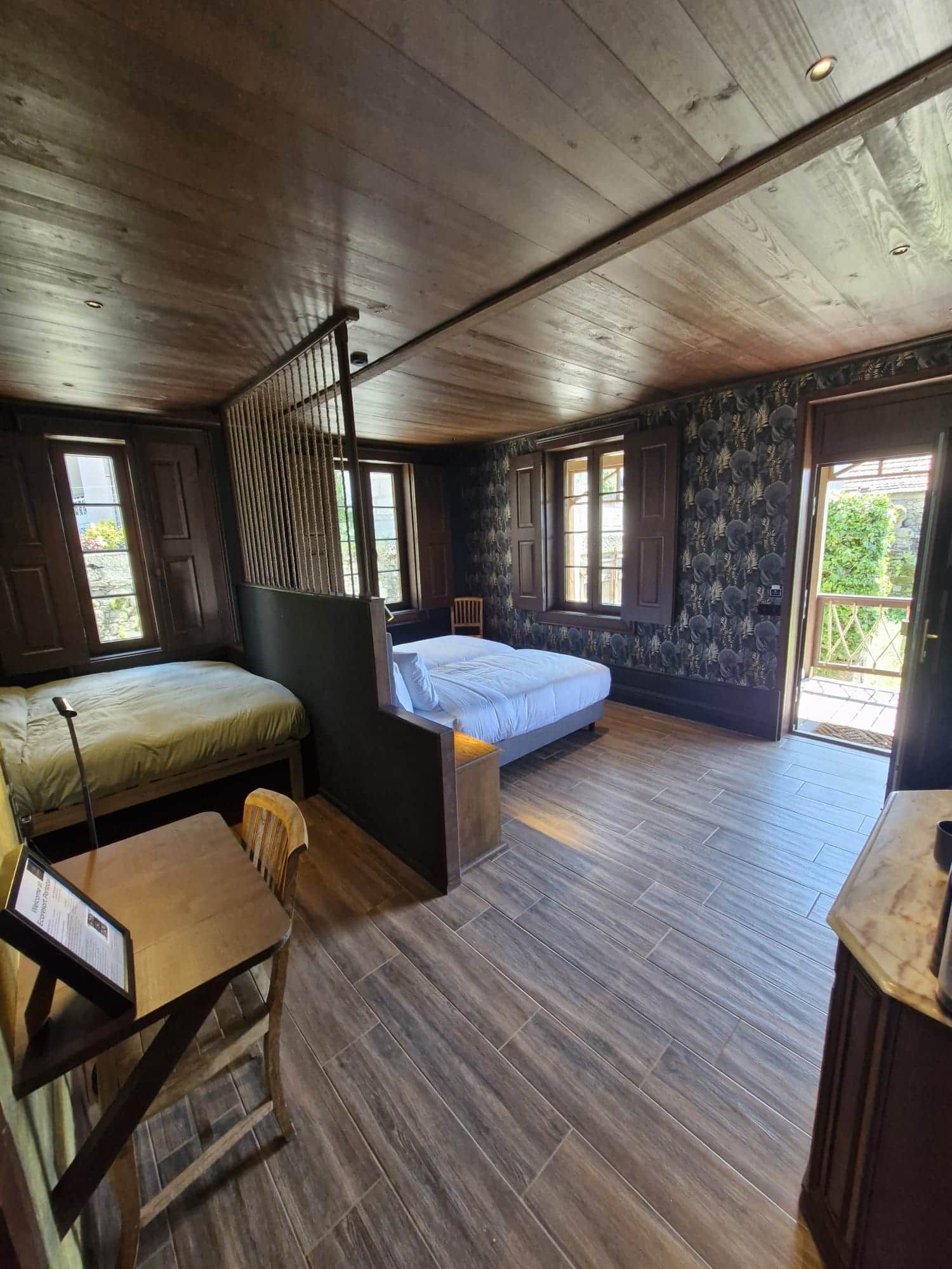 Een kamer met twee bedden, een bureau en een stoel. Er zijn ramen en een deur.