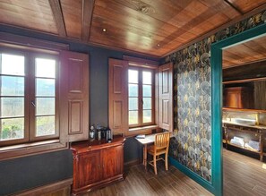 Una habitación con techo de madera, una mesa de comedor con sillas, una zona de cocina con armarios y vistas a través de las ventanas.