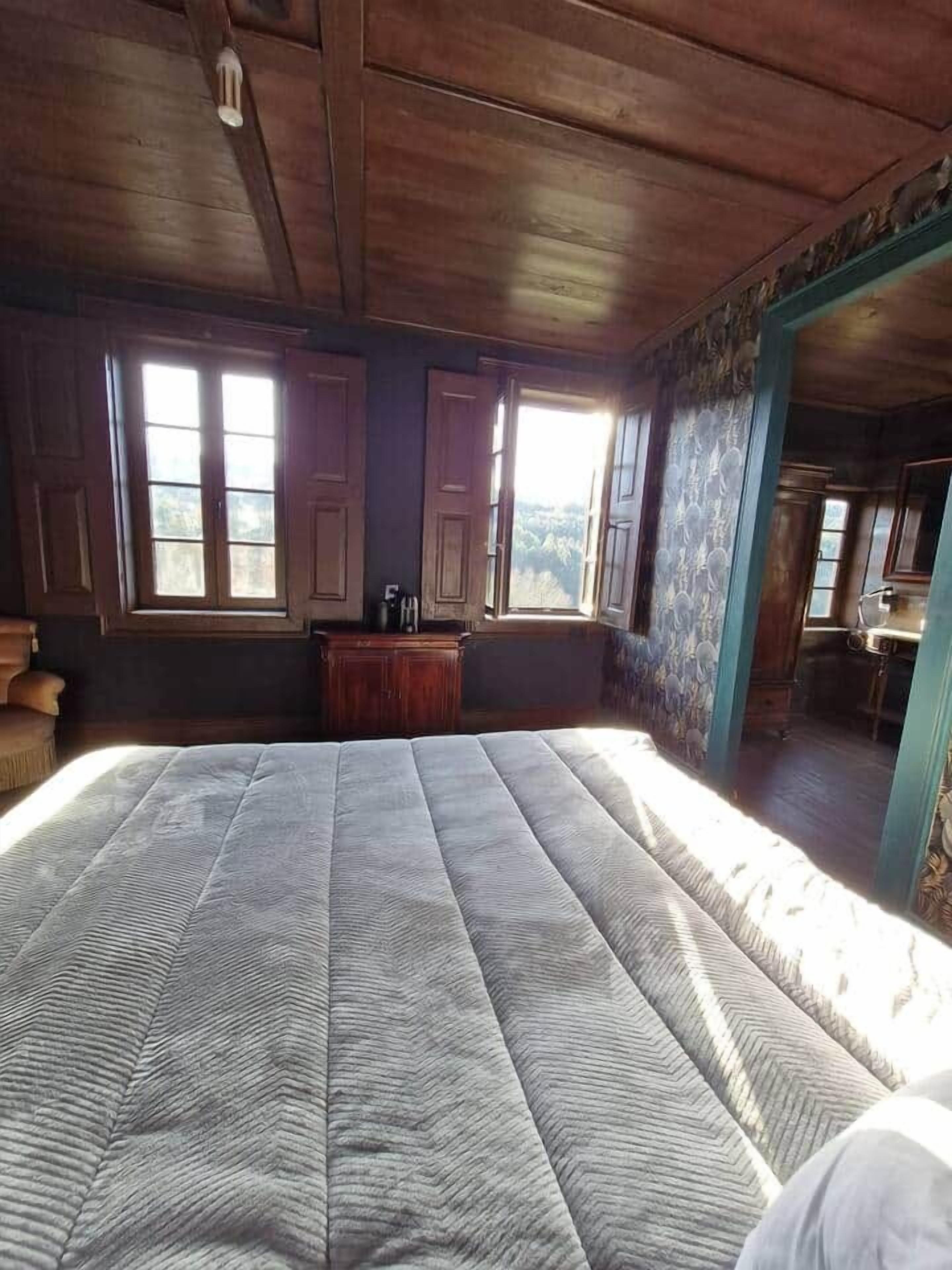 Una habitación con una cama grande, techo de madera y vistas a través de una ventana.