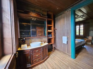 Une salle de bain en bois avec un grand miroir, un lavabo et une serviette accrochée au mur.