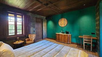 Un dormitorio con una cama grande, una silla de madera, un armario de madera y una pared verde.
