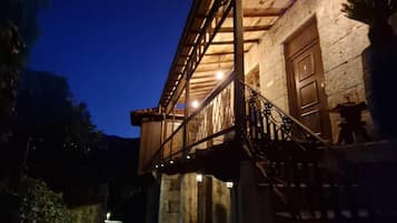 A building with a covered outdoor area, a staircase, and a stone wall.