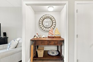A hallway with a wooden console table, a decorative mirror, and a small sailboat model. - Litchfield By The Ocean, Two bedroom condo across from Litchfield Beach (Pawleys Island)