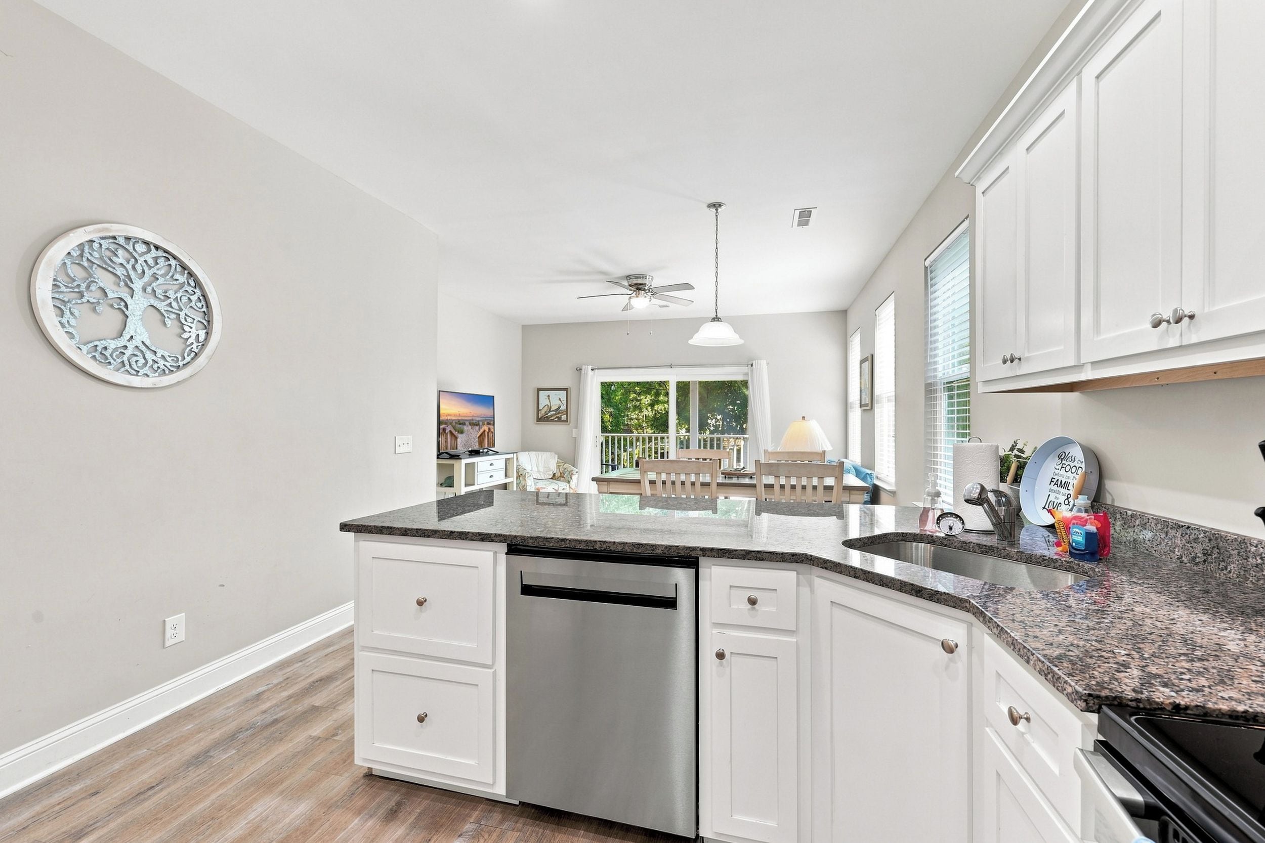A modern kitchen with white cabinetry, a granite countertop, and a dishwasher.