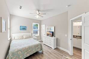 Un dormitorio con cama, cómoda, ventilador de techo y televisor.