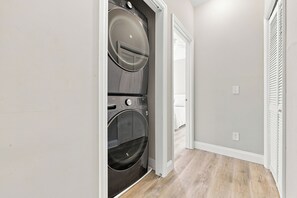 A laundry room with a built-in washer and dryer, a white door, and a wooden floor. - Murrells inlet Peeps (Murrells Inlet)