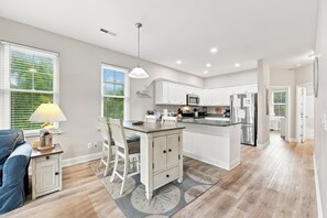 Una cocina moderna con armarios blancos, electrodomésticos de acero inoxidable y una isla central.