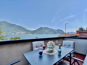 Ein Balkon mit Tisch und Stühlen, der einen Blick auf einen See und Berge bietet.