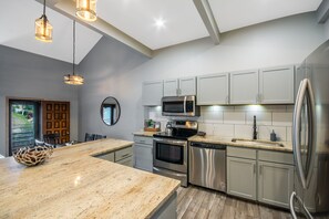 Eine moderne Küche mit Granit Arbeitsplatten, Edelstahlgeräten und Pendelleuchten.