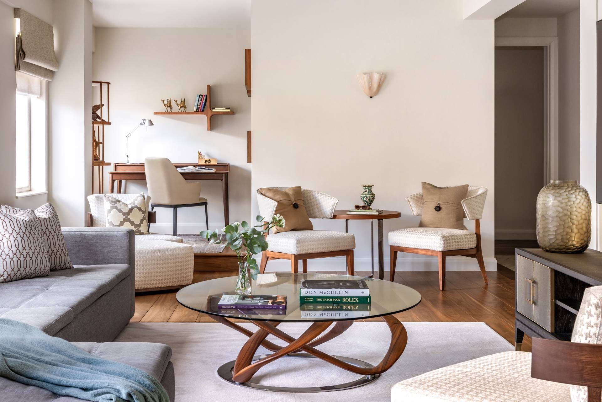 A modern living room with a sofa, two armchairs, a coffee table, and a bookshelf.