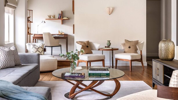 Una sala de estar moderna con un sofá, dos sillones, una mesita de centro y una estantería.