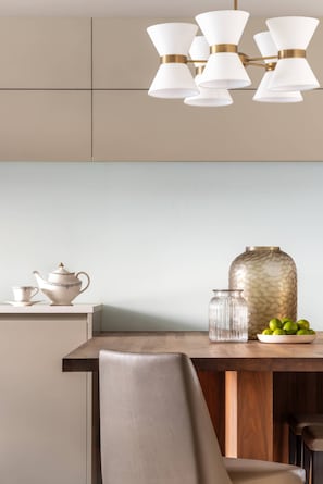 Eine moderne Küche mit einem Holztisch, einem weißen Teekessel, einem Glasbehälter und einer Schüssel mit Limetten.