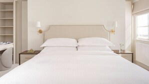 Una habitación de hotel con una cama grande, mesitas de noche, un escritorio y una silla.