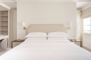 Ett hotellrum med en stor säng, sängbord, ett skrivbord och en stol.