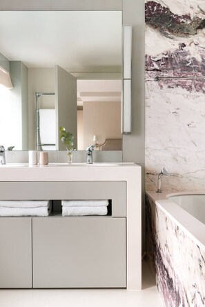 Ein modernes Badezimmer mit Marmorwand, einem großen Spiegel und einer Badewanne.