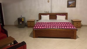 A bedroom with a wooden bed, two bedside tables, a nightstand, a ceiling fan, and a small safe. - MILANO INN HOTEL (AHODWO DABAN)