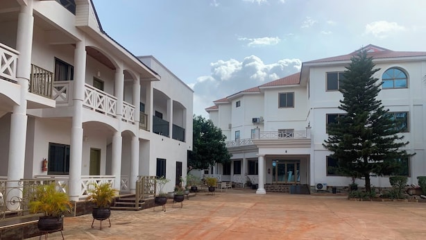 A spacious courtyard with a covered walkway, potted plants, and a building with multiple balconies and a central entrance. - MILANO INN HOTEL (AHODWO DABAN)