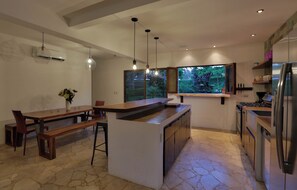 A modern kitchen with a central island, built-in appliances, and a view of greenery outside. - Casa Colibri Vista Ocotal 12 - 4BR condo & pool/ walking distance to Playa Ocotal (Playa Ocotal)