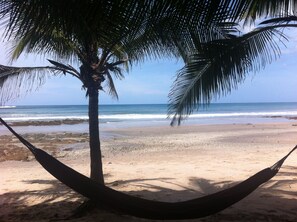 A beach scene with a hammock, palm tree, and ocean view. - Casa Colibri Vista Ocotal 12 - 4BR condo & pool/ walking distance to Playa Ocotal (Playa Ocotal)