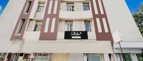 A multi-story building with a modern architectural design, featuring a central entrance with a sign that reads 'Collection'.