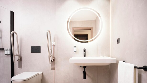 A modern bathroom with a toilet, bidet, sink, and a mirror with a light. - Alora Hotel Madrid Alcorcón (Alcorcón)