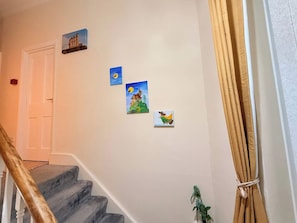 A staircase with a handrail, a door at the top, and three small paintings on the wall. - Spacious 4BR Entire House | 5 Mins to Newcastle and Gateshead Centre | Sleeps 9 (Tyne and Wear)