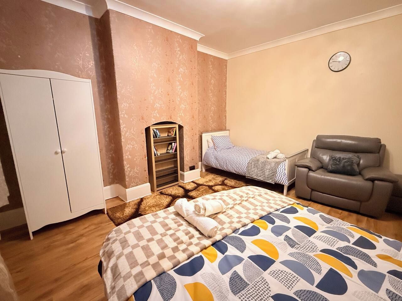 Ein Schlafzimmer mit einem Bett, einem Kleiderschrank, einer Couch und einer Uhr an der Wand.
