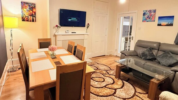 Ein modernes Wohnzimmer mit Esstisch, Sofa und Fernseher.