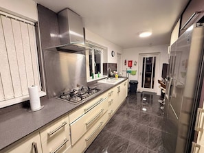 A modern kitchen with stainless steel appliances, a gas stove, and a large refrigerator. - Spacious 4BR House | 5 Mins to city | Sleeps 9 (Tyne and Wear)