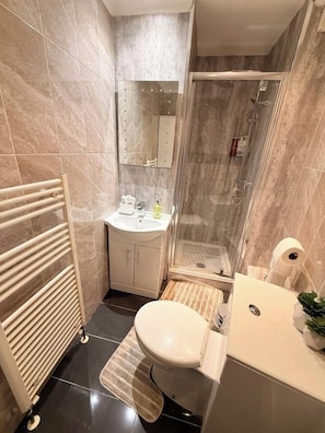 A compact bathroom with a toilet, sink, and shower area. - Spacious 4BR House | 5 Mins to city | Sleeps 9 (Tyne and Wear)