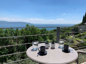 Ein runder Tisch mit Meerblick, Topfpflanzen und zwei Tassen.