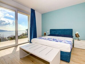 Ein Schlafzimmer mit einem Bett, Nachttischen, einer Bank und einem großen Fenster mit Blick.