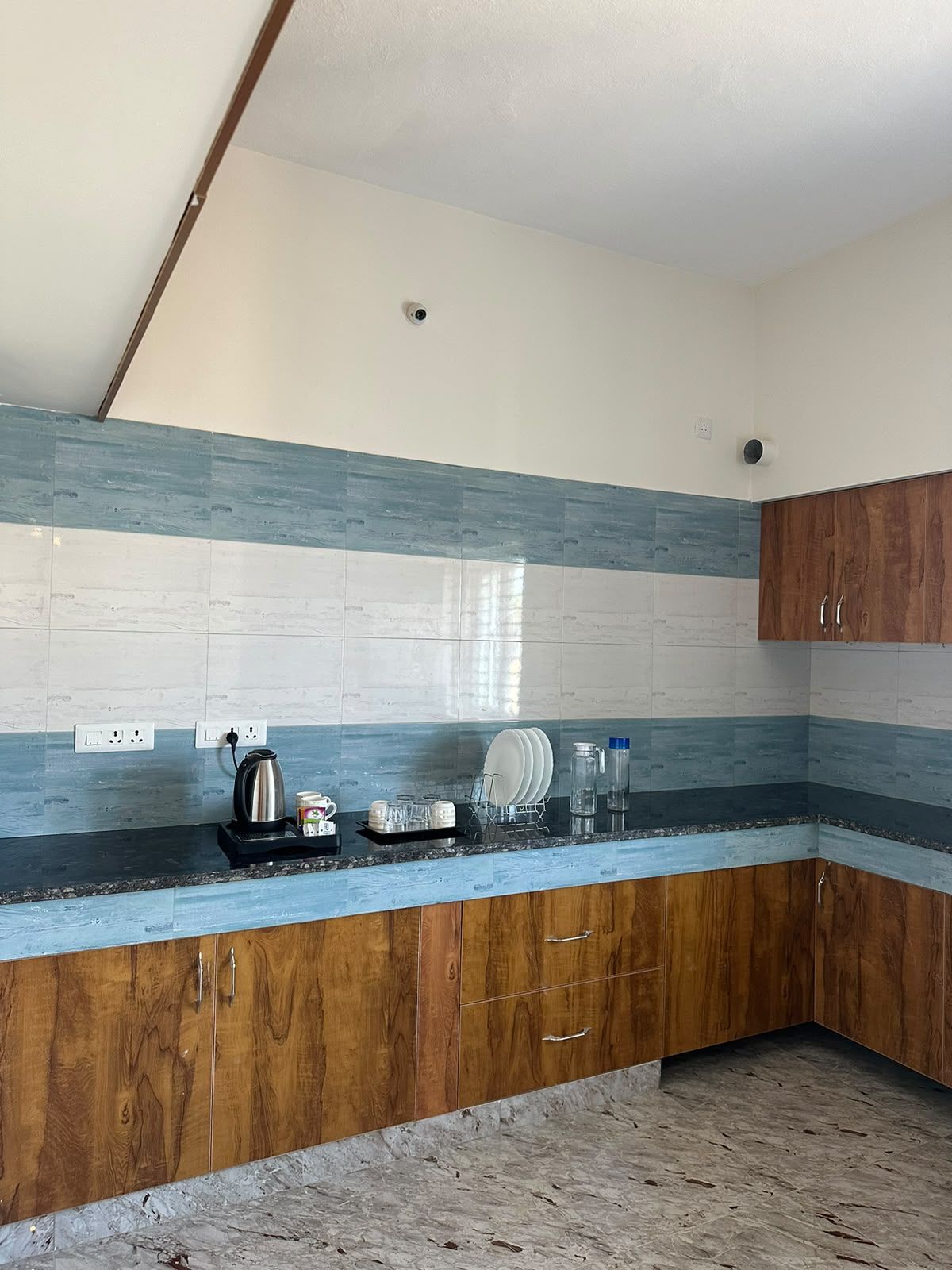 Una cocina con armarios de madera, encimera de granito y salpicadero con azulejos azules y blancos.